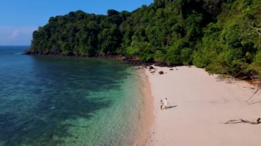 Tayland 'ın Trang kentindeki Koh Kradan adasında yürüyen bir kadın ve erkek. Yaz boyunca mercan kayalıkları ve turkuaz renkli okyanusları olan tropik plajlar, KLoh sahilinde birkaç erkek ve kadın.