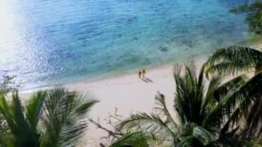 Tayland 'ın Trang kentindeki Koh Kradan adasında yürüyen bir kadın ve erkek. Yaz boyunca mercan kayalıkları ve turkuaz renkli okyanusları olan tropik plajlar, KLoh sahilinde birkaç erkek ve kadın.