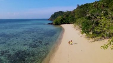 Trang Tayland 'daki tropikal ada Koh Kradan' da yürüyen bir çift kadın ve erkek. Turkuaz renkli okyanuslu güzel bir plaj.