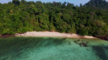 Tayland 'ın Trang kentindeki Koh Kradan adasında yürüyen bir kadın ve erkek. Yaz boyunca mercan kayalıkları ve turkuaz renkli okyanusları olan tropik plajlar, KLoh sahilinde birkaç erkek ve kadın.