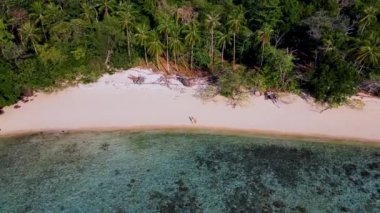 Tayland, Trang 'daki Koh Kradan adası. Yaz boyunca mercan kayalıkları ve turkuaz renkli okyanusları olan tropik plajlar, gün batımı plajında birkaç erkek ve kadın.