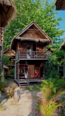 Tropik bir adanın sahilinde, ahşap bir bungalovun önündeki kadınlar. . 