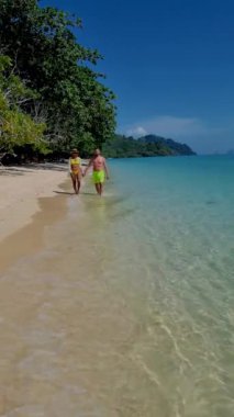 Tayland, Trang 'daki Koh Kradan adasının havadan görüntüsü. Yaz boyunca mercan kayalıkları ve turkuaz renkli okyanusları olan tropik plajlar, gün batımı plajında birkaç erkek ve kadın.