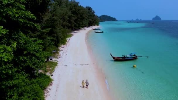 在一个阳光明媚的日子里 这个海滩最近被命名为世界上新的第一海滩 泰国海滩上有草屋色的大海 一对男女在海滩上散步 — 图库视频影像