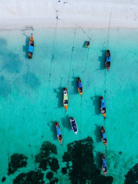 Tayland 'da Koh Lipe Adası sahilindeki drone manzarası. Okyanusta uzun kuyruklu teknelerle beyaz bir sahilde. 