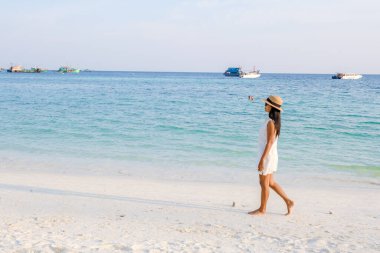Ko Lipe Adası Tayland 'da gün batımında sahilde yürüyen Asyalı kadınlar.