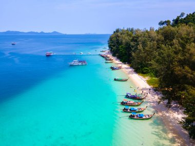 Tayland 'daki Koh Kradan adasının kumsalında insansız hava aracı görüntüsü güneşli bir günde okyanusta uzun kuyruklu teknelerle Koh Kradan Adası üzerinde hava manzarası.