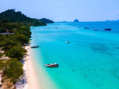 Tayland 'daki Koh Kradan adasının kumsalında insansız hava aracı görüntüsü güneşli bir günde okyanusta uzun kuyruklu teknelerle Koh Kradan Adası üzerinde hava manzarası.