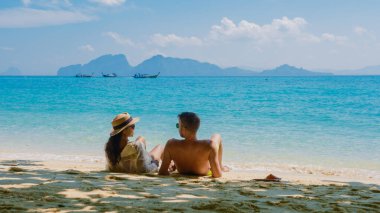 Tatil sırasında Tayland 'daki Koh Kradan adasında oturan bir çift kadın ve erkeğin arkası.