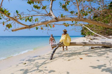 Tayland 'da Koh Kradan Adası sahilinde güneşli bir günde turkuaz renkli bir okyanusla kumsalda dinlenen bir çift kadın ve erkek.