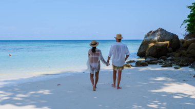 Koh Lipe Adası Güney Tayland Turkuaz renkli okyanusları ve Ko Lipe 'de beyaz kumlu plajları var. Tayland 'da tatilde olan bir çift kadın ve erkek sahilde yürüyorlar.