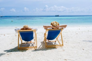 Koh Lipe Adası 'nın güney Tayland sahillerinde, turkuaz renkli okyanusları ve Ko Lipe' de beyaz kumlu plajları olan plajlarda oturan bir çift kadın ve erkek..