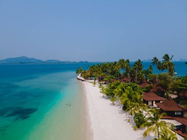 Tayland 'da Andaman Denizi' ndeki Koh Mook tropikal adası, beyaz kumlu tropik plaj ve hindistan cevizi palmiyeli turkuaz renkli okyanus. Sahildeki ahşap bungalovlar