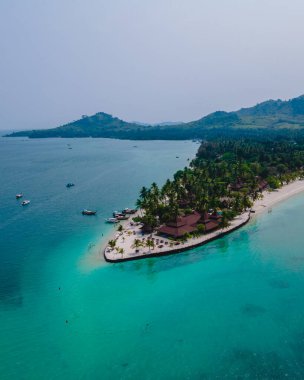 Tayland 'da Andaman Denizi' ndeki Koh Mook tropikal adası, beyaz kumlu tropik plaj ve hindistan cevizi palmiyeli turkuaz renkli okyanus. Tropik bir adanın insansız hava görüntüsü