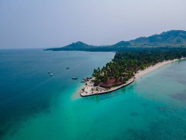 Tayland 'da Andaman Denizi' ndeki Koh Mook tropikal adası, beyaz kumlu tropik plaj ve hindistan cevizi palmiyeli turkuaz renkli okyanus. Tropik bir adanın insansız hava görüntüsü