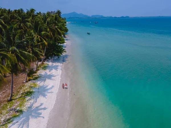 タイのアンダマン海にあるコ ムック熱帯の島で休暇中の男性と女性のカップルヤシの木とビーチを歩く男性と女性 — ストック写真