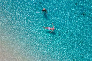 Beyaz tropikal plajları ve turkuaz renkli okyanusları olan Koh Kradan Adası 'nda yüzen bir çift. Mavi bir okyanustaki erkek ve kadınlar yukarıdan drone ile görüldüler.