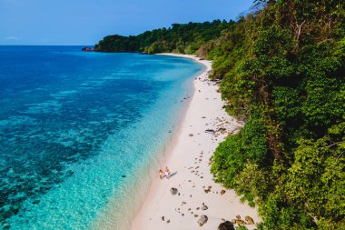 Beyaz tropikal bir plaj ve turkuaz renkli bir okyanusla Koh Kradan Adası sahilinde yürüyen bir çift. Erkekler ve kadınlar yukarıdan Tayland 'da tatil sırasında İHA ile görülmüşler.