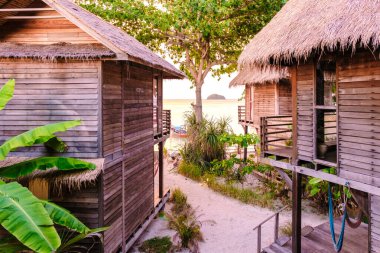 Tayland 'da bir adanın sahilindeki bungalovda, plajda palmiye ağaçları olan ahşap bir villa.