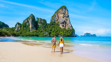 Railay Beach Krabi Tayland, Railay Krabi 'nin tropikal plajı, kumsalda bir çift kadın ve erkek, güneşli bir sabahta Tayland' da huzurlu bir Railay Plajı manzarası.