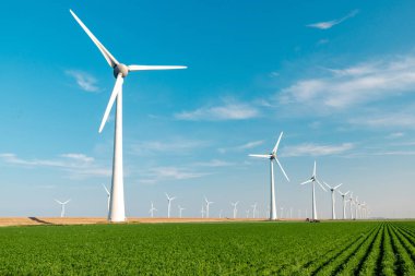 Mavi gökyüzü, yeşil tarım arazisi ve okyanusta yel değirmeni türbinleri parkı olan yel değirmeni parkı. Hollanda Avrupa