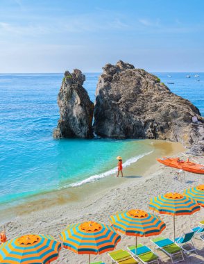 Asyalı kadınlar Monterosso Cinque Terre İtalya 'nın bir parçası olan Monterosso Sahili' ni, Mare Spiaggia di Fegina Sahili 'ndeki sandalyeleri ve şemsiyeleri ziyaret ediyorlar.