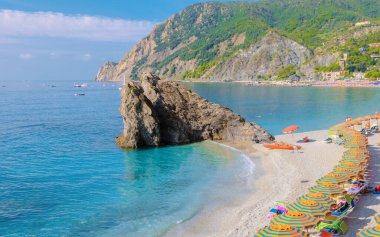 Pibble Beach Monterosso tatili Cinque Terre Monterosso al Mare Sandalyeleri ve şemsiyeler yaz tatili sırasında Cinque Terre İtalya 'nın bir parçası olan Spiaggia di Fegina plajını dolduruyor.