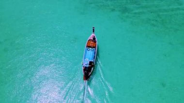 Tayland 'ın güneyindeki Koh Kradan Adası sahilde uzun kuyruklu tekneleri ve Trang Tayland' da güneşli bir günde turkuaz renkli bir okyanusu var.