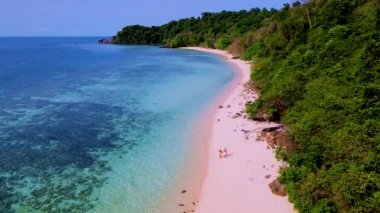 Güneşli bir günde Tayland 'da Koh Kradan Adası sahilinde turkuaz renkli bir okyanusu olan bir çift kadın ve erkek.