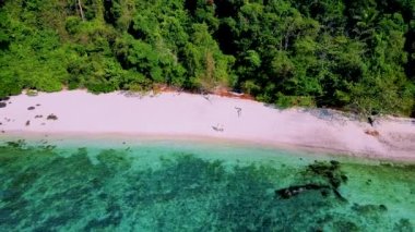 Güneşli bir günde Tayland 'da Koh Kradan Adası sahilinde turkuaz renkli bir okyanusu olan bir çift kadın ve erkek.