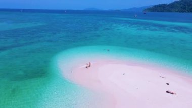 Kuzey sahilinde Koh Lipe Adası Satun Tayland 'da bir kumsal barı. Ko Lipe 'in mavi okyanusunda kumsalda yürüyen bir çift kadın ve erkek.