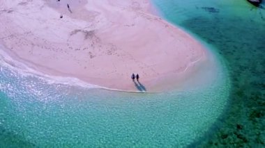 Kuzey sahili, Koh Lipe Adası Satun Tayland 'da tropikal plajı ve turkuaz renkli okyanusu olan bir kumsal. Ko Lipe 'in mavi okyanusunda kumsalda yürüyen bir çift kadın ve erkek.