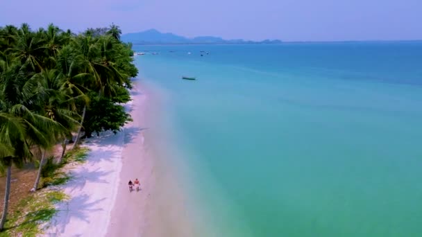 ムック島またはコ ムック トラット タイはヤシの木がある熱帯の白いビーチです タイでの休暇中の男女のカップル晴れた日にビーチを歩く — ストック動画