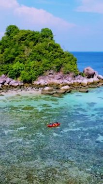 Koh Lipe Adası yakınlarındaki küçük bir tropikal adada kanoyla gezen bir çift erkek ve kadın güneşli bir günde tropik bir plaj ve hindistan cevizi renkli bir okyanusu olan Satun Tayland.