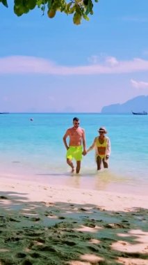 Tayland 'da güneşli bir günde, Tayland' ın Koh Kradan Adası sahilinde turkuaz renkli bir okyanusu olan bir çift kadın ve erkek.