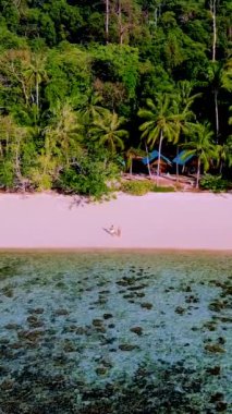 Güneşli bir günde, Tayland 'da Koh Kradan Adası sahilinde turkuaz renkli bir okyanus ve insansız hava aracı manzaralı bir çift kadın ve erkek.