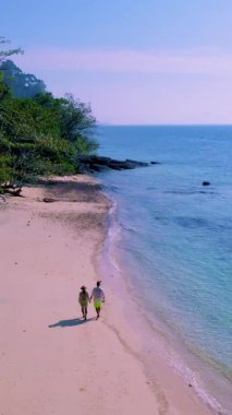 Tayland 'da güneşli bir günde, Tayland' ın Koh Kradan Adası sahilinde turkuaz renkli bir okyanusu olan bir çift kadın ve erkek.