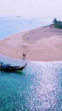 Kuzey sahili, Koh Lipe Adası Satun Tayland 'da tropikal plajı ve turkuaz renkli okyanusu olan bir kumsal. Ko Lipe 'in mavi okyanusunda kumsalda yürüyen bir çift kadın ve erkek.