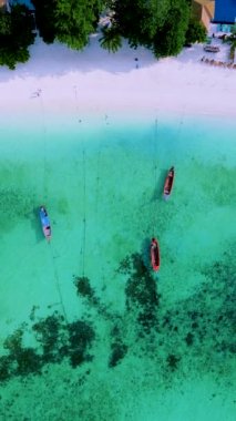 Koh Lipe Adası Satun Tayland. Tropikal bir plajı ve turkuaz renkli okyanusu var. Güneşli bir günde kumsalda uzun kuyruklu tekneleri var.