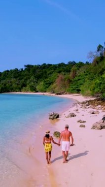 Güneşli bir günde, Tayland 'da Koh Kradan Adası sahilinde turkuaz renkli bir okyanus ve insansız hava aracı manzaralı bir çift kadın ve erkek.