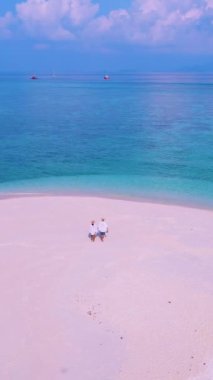 Kuzey sahili, Koh Lipe Adası Satun Tayland 'da tropikal plajı ve turkuaz renkli okyanusu olan bir kumsal. Ko Lipe 'in mavi okyanusunda kumsalda yürüyen bir çift kadın ve erkek.