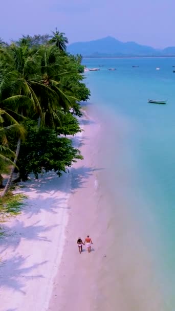 ムック島またはコ ムック トラット タイはヤシの木がある熱帯の白いビーチです タイで休暇中の男性と女性のカップルがビーチを歩く — ストック動画