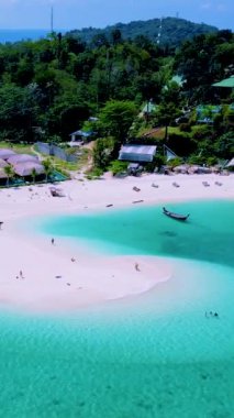 Koh Lipe Adası Satun Tayland 'daki kumsalda tropikal bir plaj ve turkuaz renkli bir okyanus. Tatil sırasında Ko Lipe 'nin mavi okyanusunda bir kumsalda yürüyen bir çift kadın ve erkek.