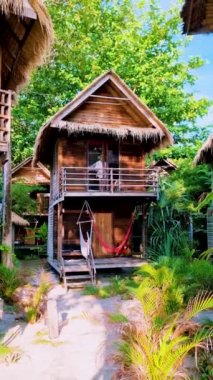 Tropik bir adanın sahilinde, ahşap bir bungalovun önündeki kadınlar. . 