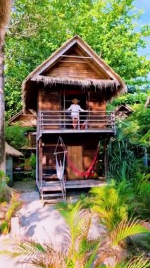 Tropik bir adanın sahilinde, ahşap bir bungalovun önündeki kadınlar. . 