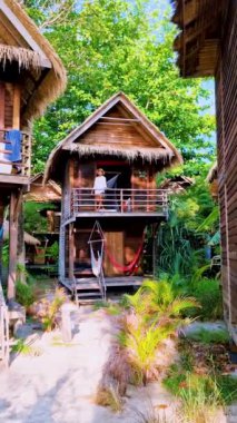 Tropik bir adanın sahilinde, ahşap bir bungalovun önündeki kadınlar. . 