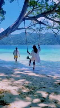 Ko Ra Wi Adası Tarutao Ulusal Parkı, Satun Eyaleti, Tayland sahilinde ip salıncaklı bir çift kadın ve erkek.