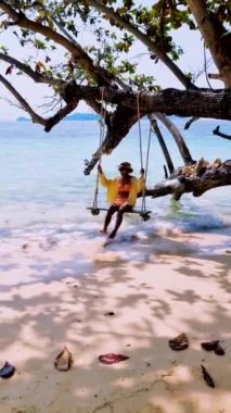 Tayland adası Koh Kradan Trang Güney Tayland sahilinde salıncakta sallanan kadınlar. Tayland 'da tatilde olan çift.