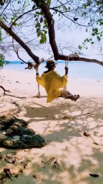 Tayland adası Koh Kradan Trang Güney Tayland sahilinde salıncakta sallanan kadınlar. Tayland 'da tatilde olan çift.
