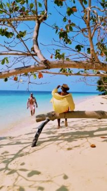 Güneşli bir günde, Tayland 'da Koh Kradan Adası sahilinde turkuaz renkli bir okyanus ve insansız hava aracı manzaralı bir çift kadın ve erkek.